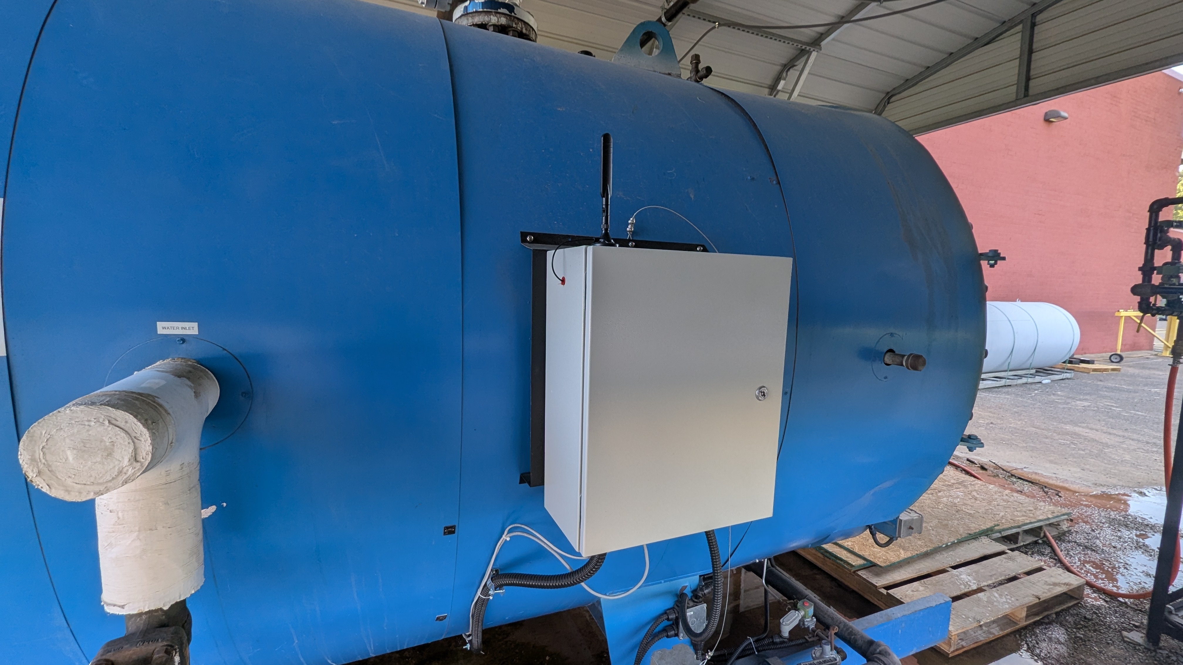 Squawkbox monitoring enclosure mounted on a large blue horizontal boiler tank